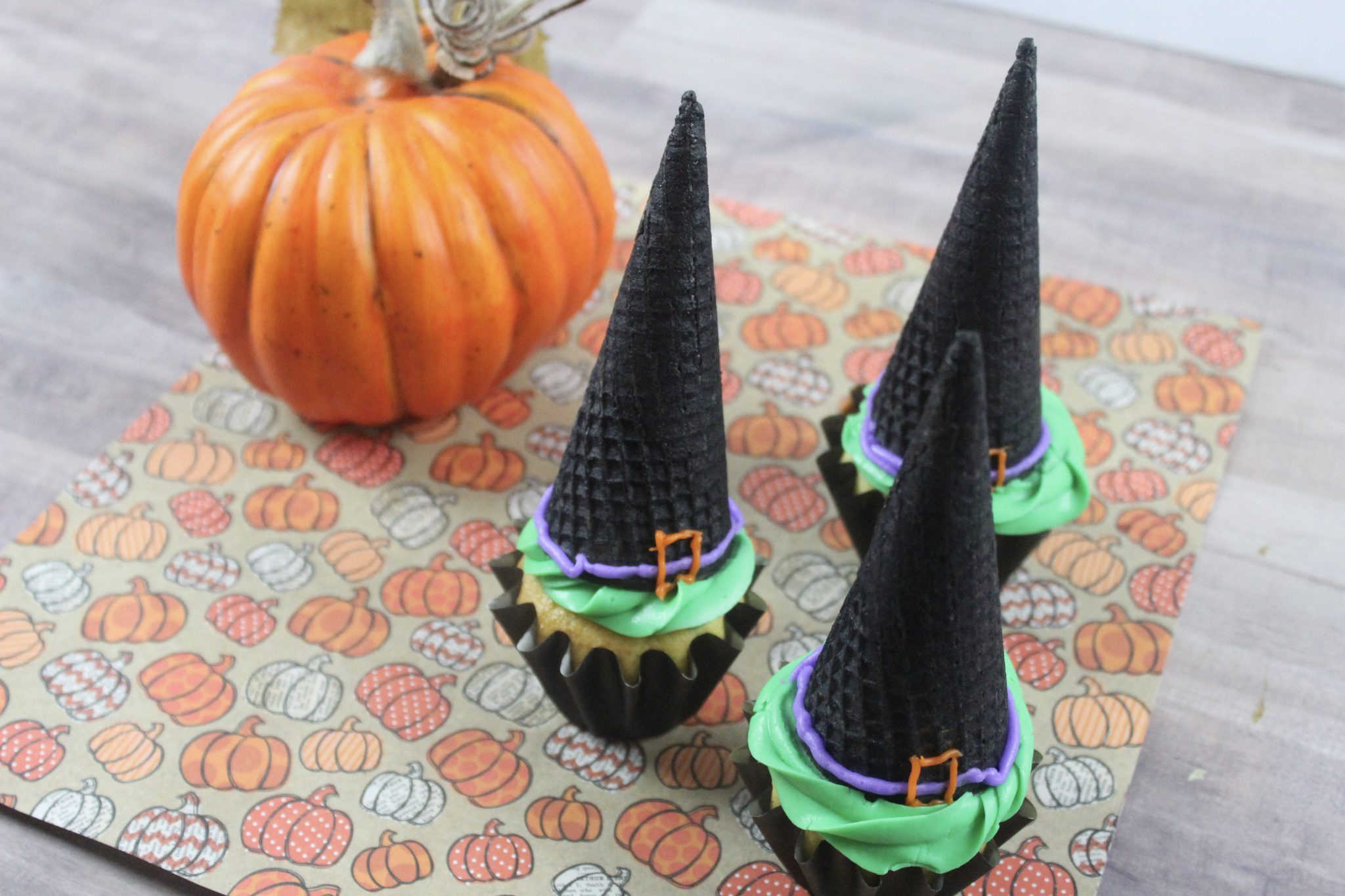 witch hat cupcakes on pumpkin printed napkin with small pumkpin in background